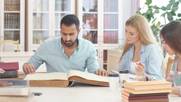 Handsome Arabian Young Bearded Man Surrounded By Multiracial Students Holding in Hands Big Ancient alt