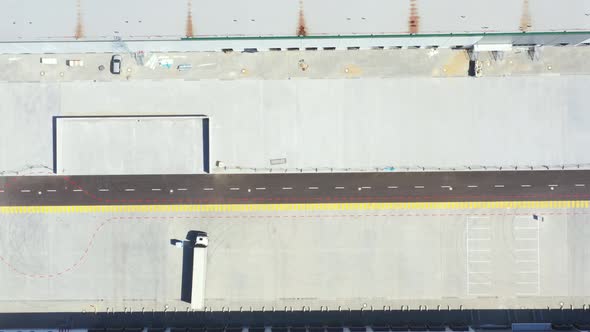 Aerial Shot of Industrial Warehouse Loading Dock where Many Truck with Semi Trailers Load Merchandis alt