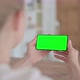 Rear View of Beautiful Woman Holding Smartphone with Green Chroma Screen