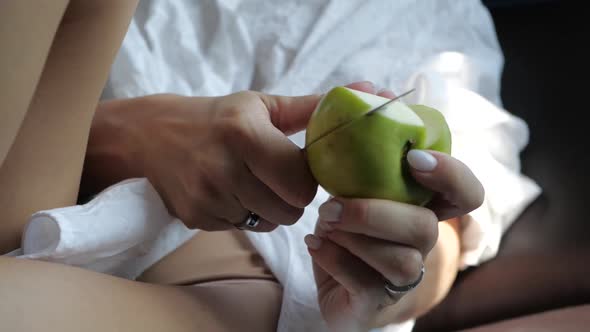 the Girl Sexually Cuts an Apple with a Knife Lying with Bare Legs