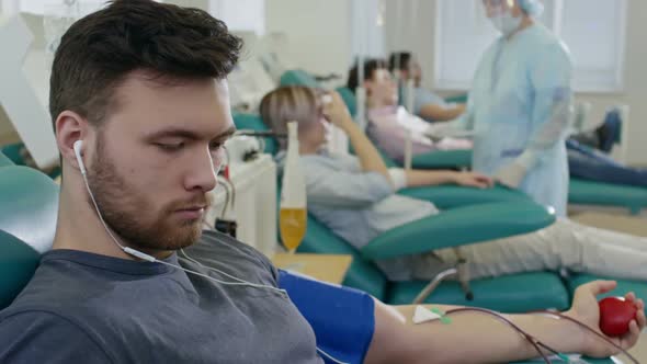 Man Listening to Music with Headphones During Giving Blood alt