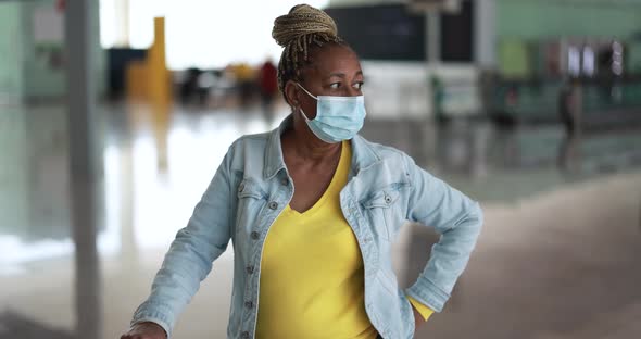 Mature african woman wearing safety face mask inside international airport alt