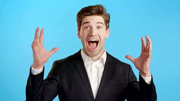 Amazed Business Man Shocked, Saying WOW. Handsome Businessman in Suit Surprised To Camera Over Blue alt