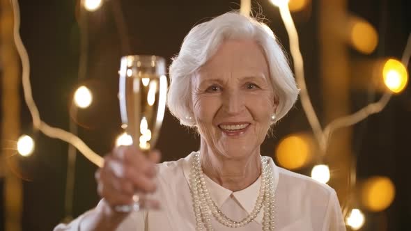 Happy Elderly Woman Raising Glass of Champagne alt