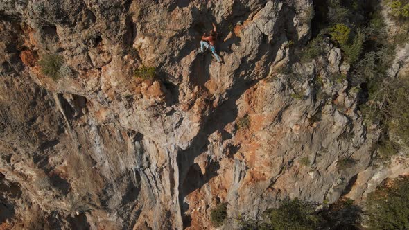 Aerial Drone POV of Strong Muscular Man Climbing Challenging Route on Vertical Crag with Tufa alt