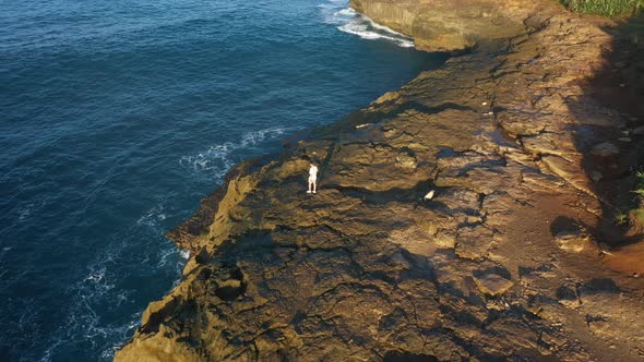 Epic adventure seeker drone shot of urban nomad traveler, hipster young millennial man stand on edge alt