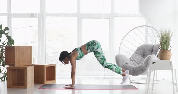 African american woman in sportswear doing jump squat.