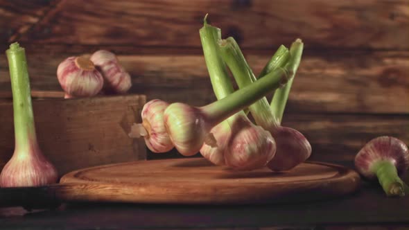 Super Slow Motion Garlic Falls on a Cutting Board on a Wooden Background alt
