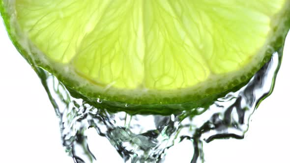 Super Slow Motion Macro Shot of Flowing Water From Lime Slice on White Background at 1000Fps alt