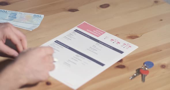 A renter reading and signing agreement get keys to a new home alt