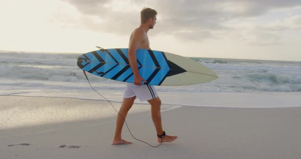 Man walking with surfboard at beach 4k
