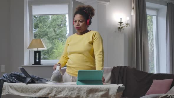 Exhausted Dissatisfied Young African American Woman Ironing Business Graph with Iron alt