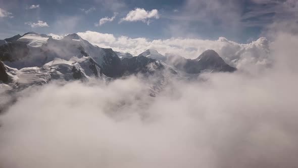 Aerial approach through the clouds in the swiss alps with the Mountain range of the Eiger, Fiescherh alt