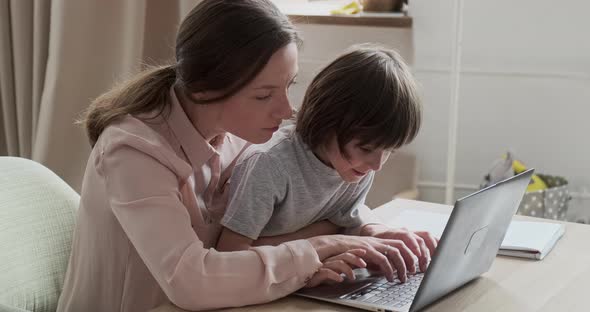 Mom and Son are Working on the Computer Together Learning Programming and Enjoying Video Games alt