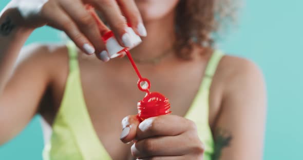 A girl blowing bubbles at the camera alt