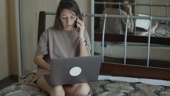 Woman Sitting on Bed and Working Remotely