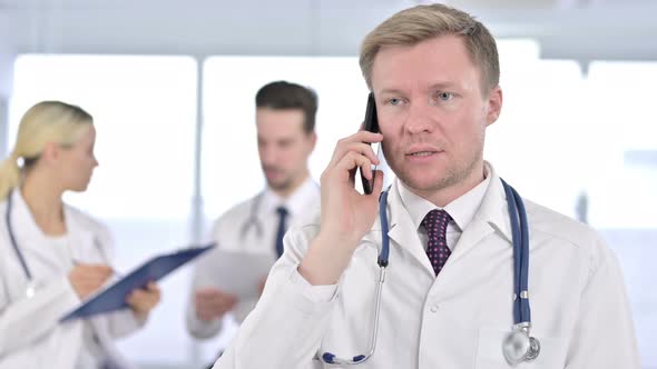 Portrait of Focused Male Doctor Talking on Smartphone alt