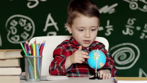 Home education for kids boy looking at globe. A child studies the globe at home. Teaching a child alt