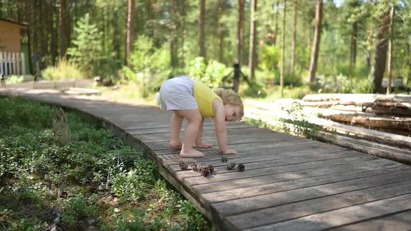 Little Funny Cute Blonde Girl Child Toddler in Yellow Undershirt and Grey Shorts Walking Playing on