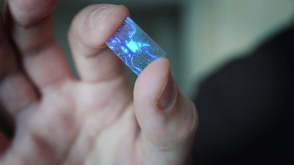 Close Up Macro Zoom Shot a Person is Holding a Microchip with Holographic Glowing Elements.	 alt