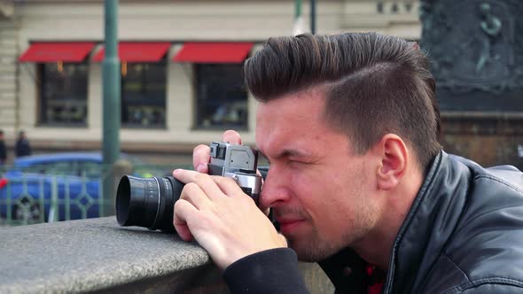 A Young Handsome Man Takes Photos with a Camera - Closeup From the Side - a Busy Street alt