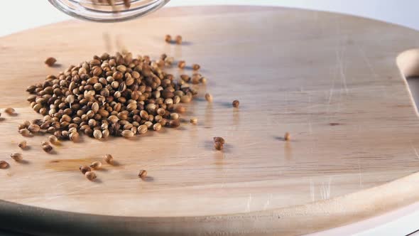 Slow Motion Shot of Coriander Seeds Being Poured on to a Wooden Board alt