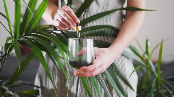 Woman Hand Holding Dropper with Green Chlorophyll at Home alt
