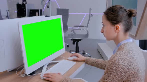 Woman Looking at White Monitor of Desktop Computer with Blank Green Display