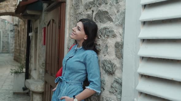 Charming Pretty young woman with brunette hair in denim overalls smiling and looking at camera alt