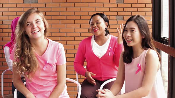 Multiethnic women wearing pink ribbons talking and sharing for breast cancer awareness campaign