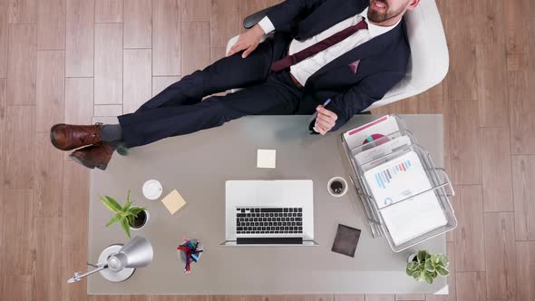 Top View of Successful Businessman in Suit with His Feet on the Desk alt