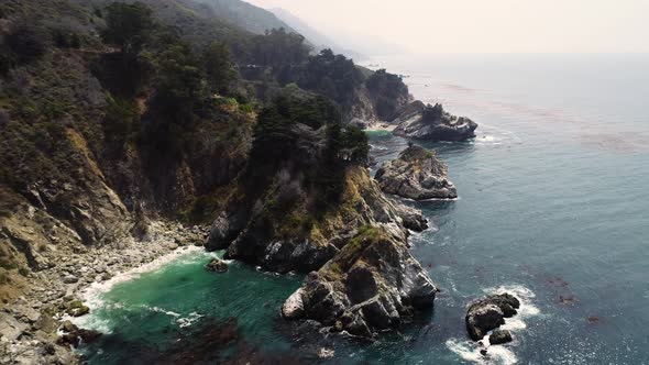 Aerial view of coastal rock formation with an dense pine tree forest, U.S.A. alt