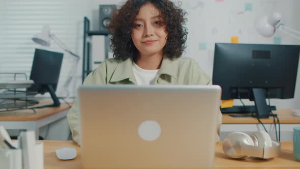 Asian Indian Businesswoman works computer smiling looking at camera with a positive