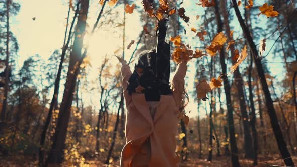 Happy Young Woman Is Tossing Leaves Up and Whirling Joyfully in Autumn Woodland alt