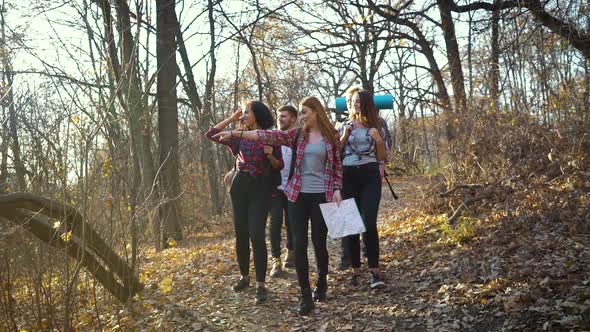 Group of hikers walking in autumn forest with paper map alt