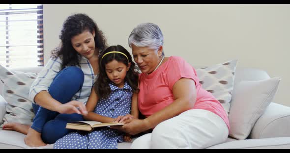 Mother and daughter reading book in living room 4k alt