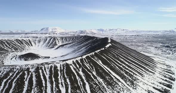 aerial of the Hverfjall volcano in Iceland and surrounding mountains covered in snow alt