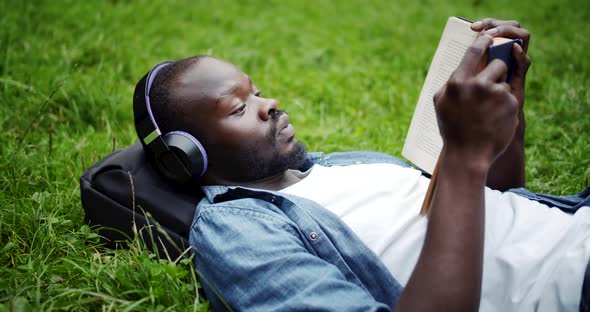 African-American Man Lying on Lawn with Book