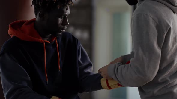 Assistant Helping to Put on Boxing Gloves to a Male Athlete Tie a Lace Close Up alt