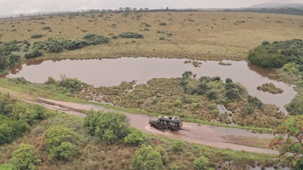 Four wheel drive vehicle driving through muddy puddle in Aberdare National Park, Kenya, Africa, Aerial  alt