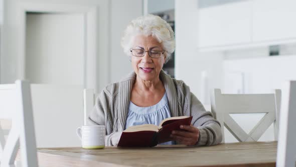 African american senior woman reading a book while sitting at home alt