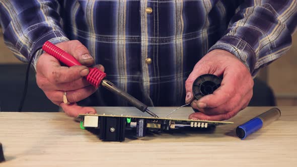Hands of a Master Closeup a Man Solders an Electronic Circuit Board alt