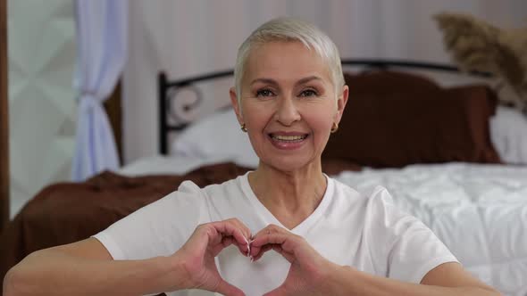 Closeup of Senior Woman at Bedroom Making a Heart with Her Hands