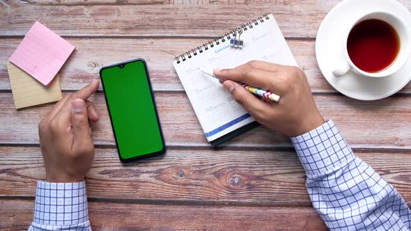 Deadline Concept with Hand Marking Date on Calendar and Using Smart Phone alt