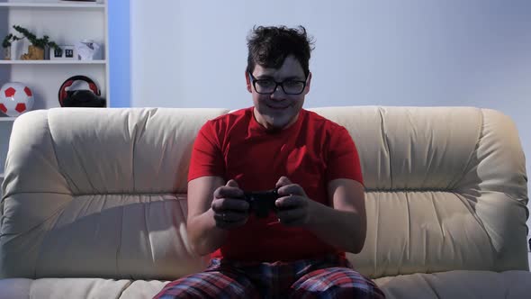 Bespectacled Man Playing Video Game While Sitting on the Couch alt