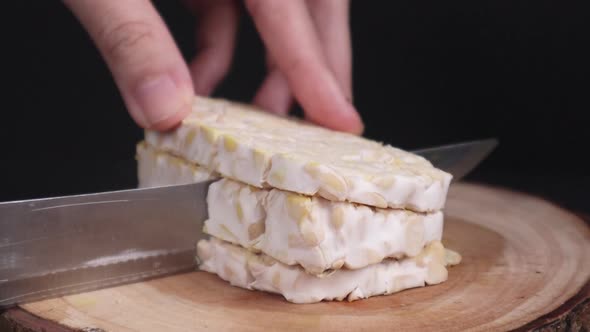 Close Up   Chopping A Raw Tempeh Into Cubes On A Cutting Board alt