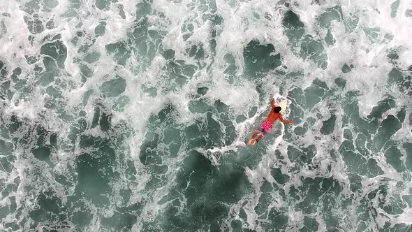 Top View Of Male Surfer Lying And Swimming On A Surfboard Afloat On Wavy Ocean Surface In La Ticla, alt