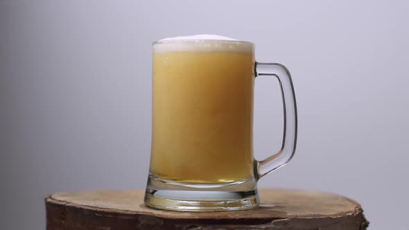 Slow Motion Shot of Light Beer Is Poured Into a Beer Glass with a Handle, a Lot of Bubbles and Foam alt