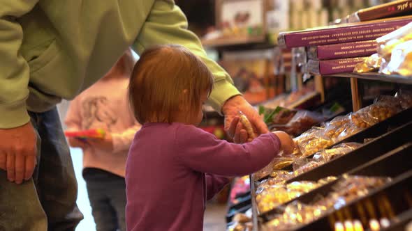 Little Girl is Choosing Sweets with Dad in Candy Shop