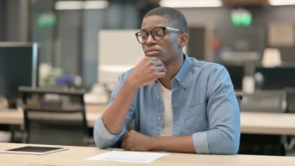 Young African American Man Sitting in Office and Thinking alt